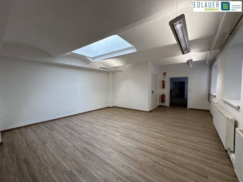 Großer, heller Raum mit Laminatboden, Oberlicht und effizienter Deckenbeleuchtung, ideal für Büro oder Lager.
