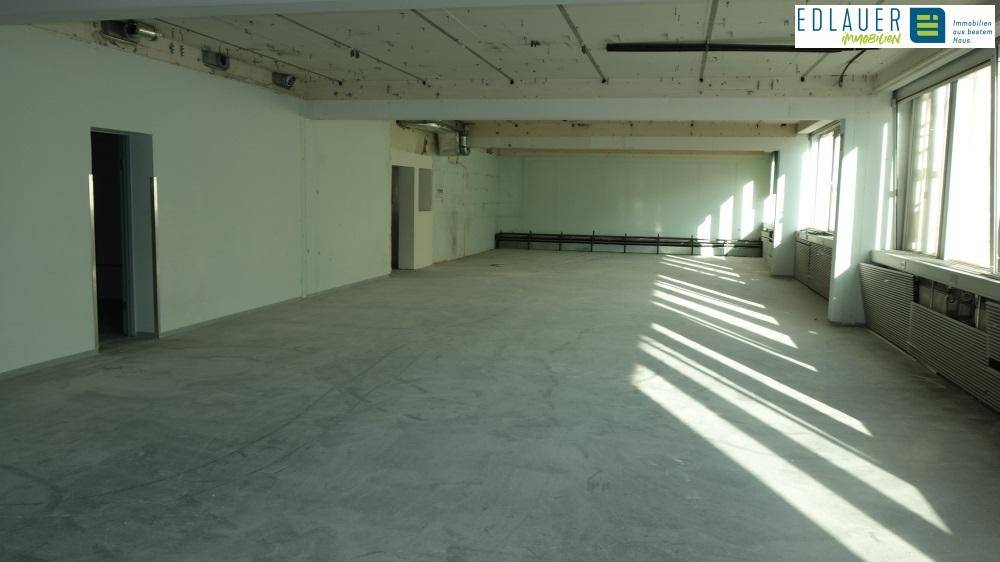 Großer, heller Gewerberaum mit Betonboden und sichtbaren Deckeninstallationen, ideal für individuelle Gestaltung.