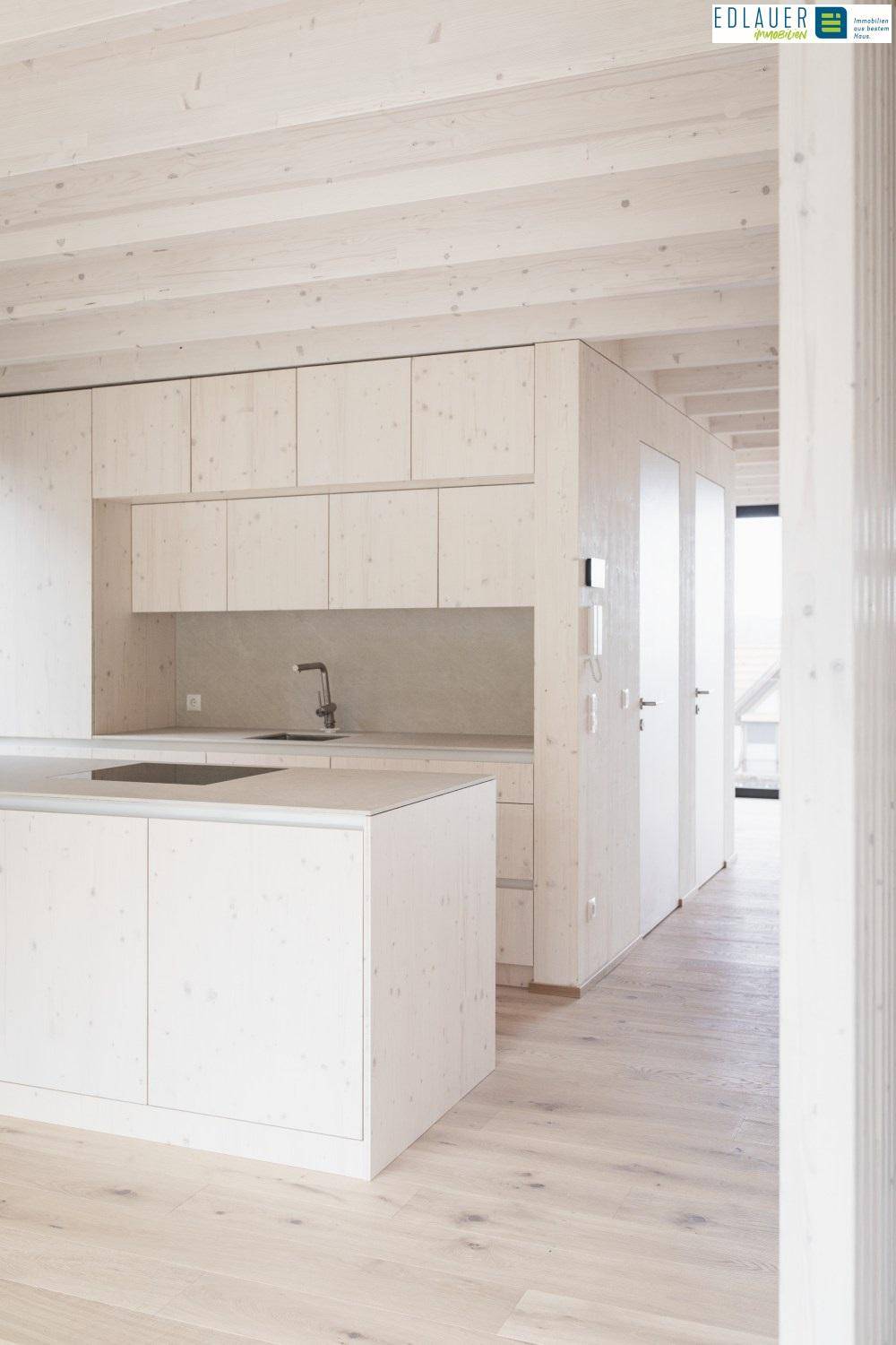 Helle Einbauküche mit Kücheninsel und Holzbalkendecke, die viel natürliches Licht erhält.