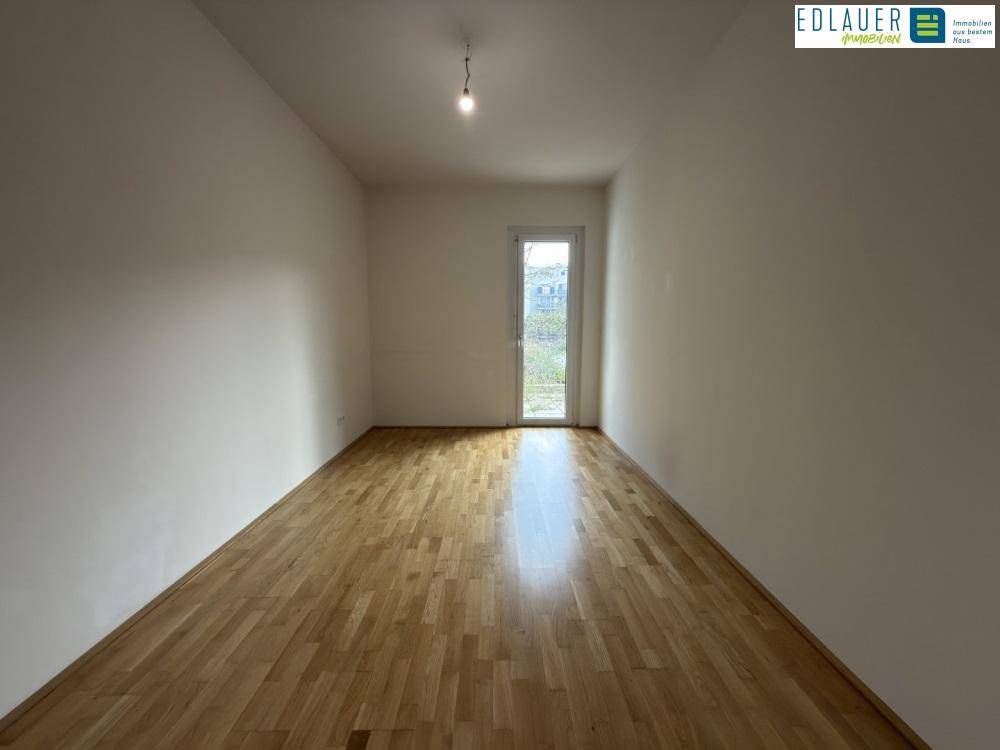 Freundliches Zimmer mit Parkettboden und Zugang nach draußen, vielseitig nutzbar.