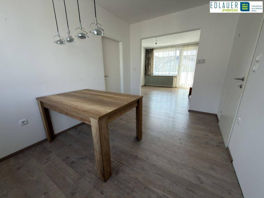 Essbereich mit Holztisch und Blick in den angrenzenden Wohnbereich.