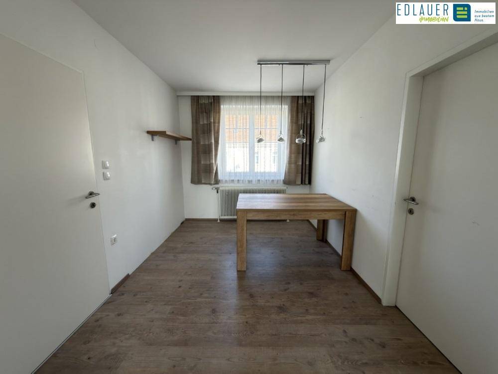 Esszimmer mit Holztisch, Laminatboden und Pendelleuchte über dem Tisch.