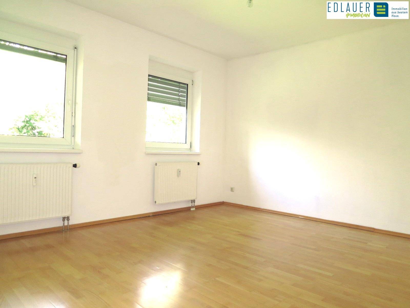 Leeres Zimmer mit Parkettboden und Fenster, ideal für Schlaf- oder Kinderzimmer.