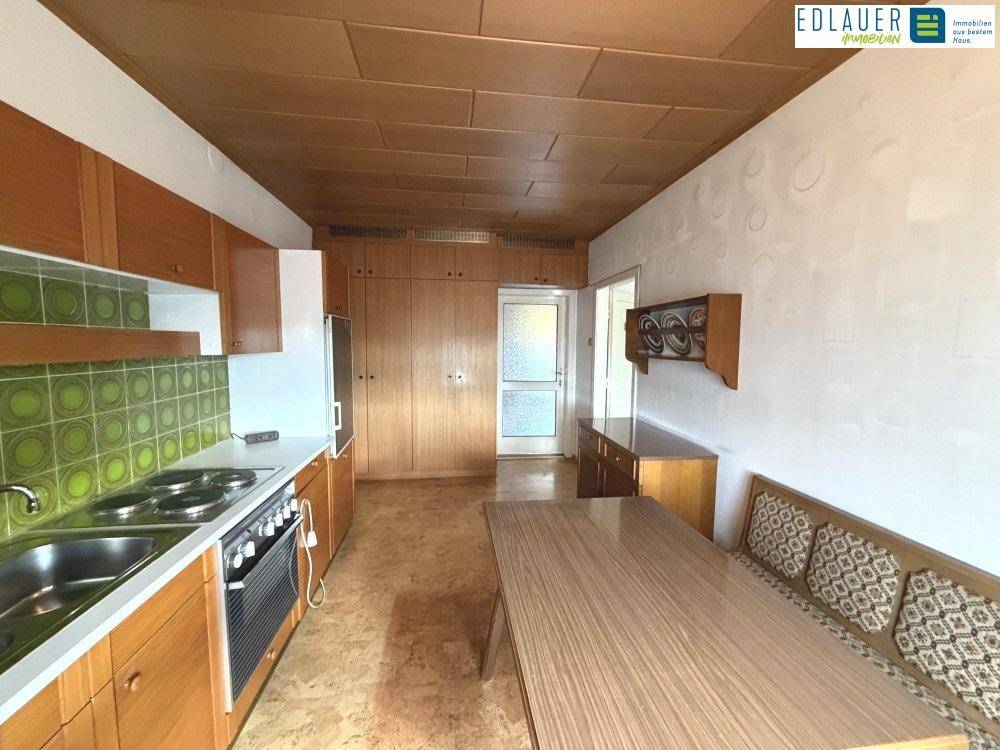 Funktionale Küche mit Holzschränken, Essbereich und traditionellen Fliesen, bietet viel Stauraum.