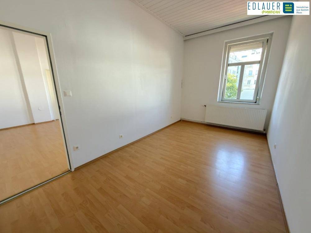 Helles Schlafzimmer mit Laminatboden und einem Fenster, bietet eine ruhige Atmosphäre.
