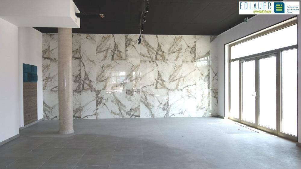 Moderner Gewerberaum mit einer markanten Wand aus großformatigen Marmorfliesen und großen Fenstern.
