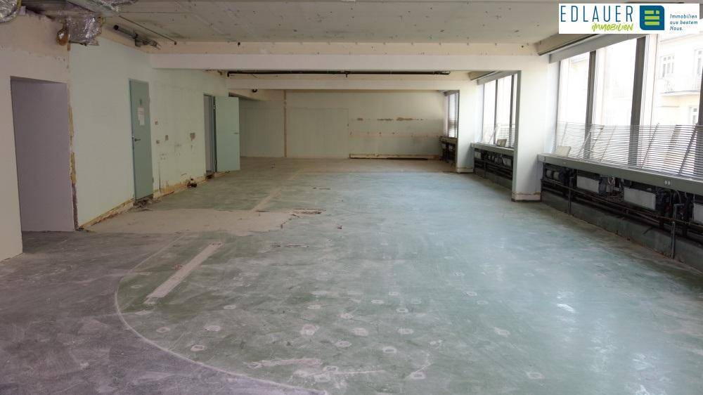 Geräumiger Gewerberaum mit Betonboden und großen Fenstern, ideal für einen Umbau nach eigenen Vorstellungen.