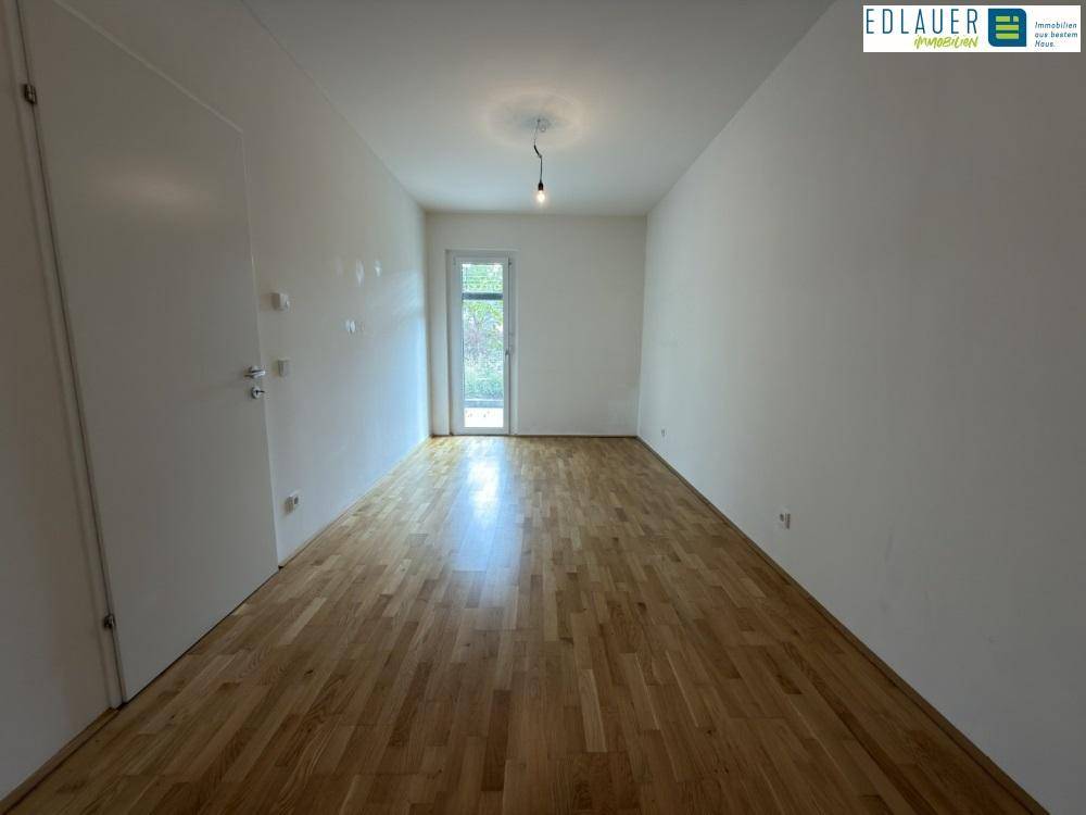 Helles Zimmer mit Parkettboden und Zugang zu einem französischen Balkon, ideal als Schlaf- oder Arbeitszimmer.