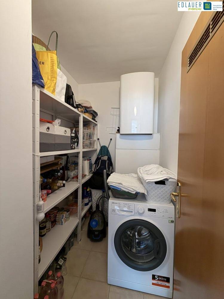 Praktischer Abstellraum mit Regalen, Waschmaschine und Warmwasserboiler.