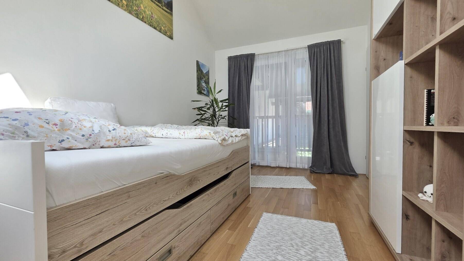 Schlafzimmer mit Holzboden, Einzelbett und Zugang zu einem Außenbereich.