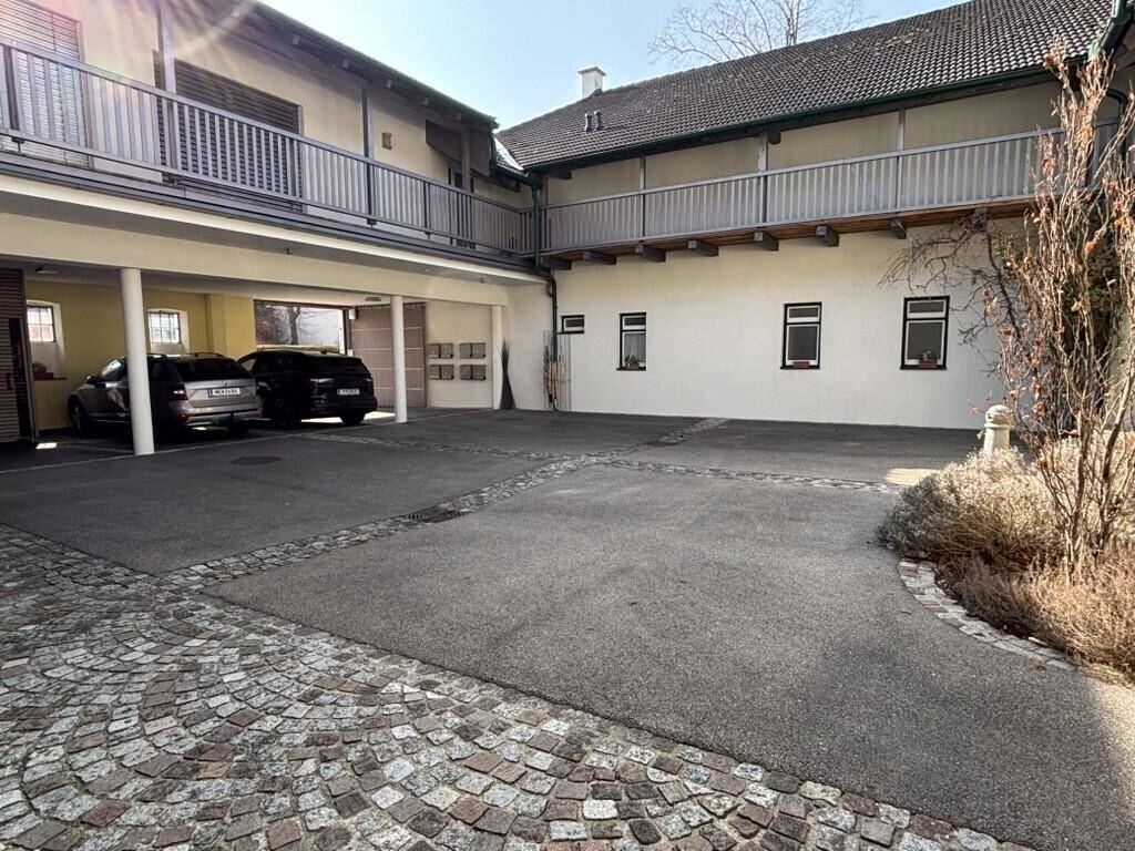 Innenhof mit Parkplätzen, Kopfsteinpflaster und einem überdachten Bereich.