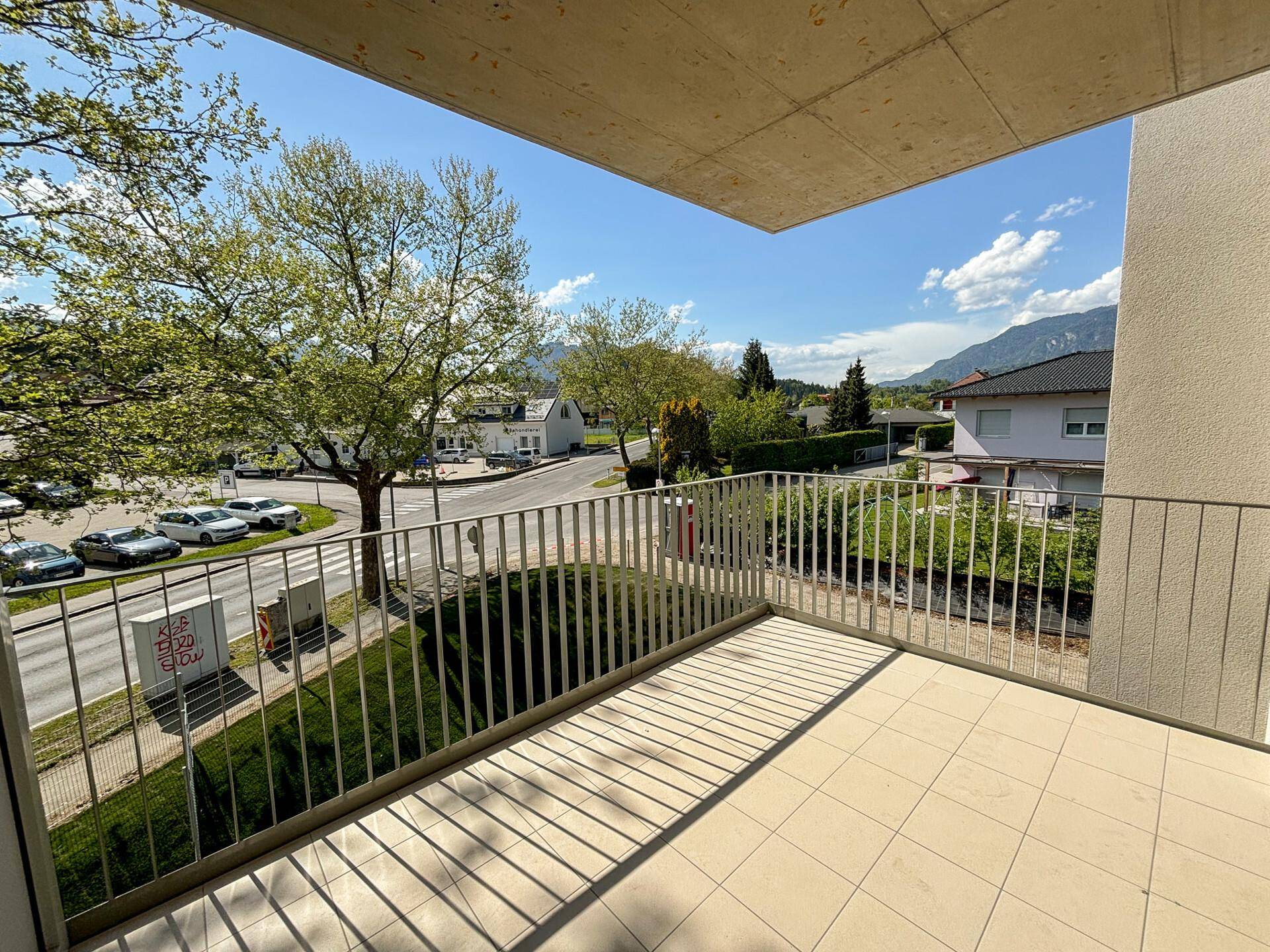 Balkon mit Fliesenboden und Blick auf die Straße sowie die umliegende Bebauung.