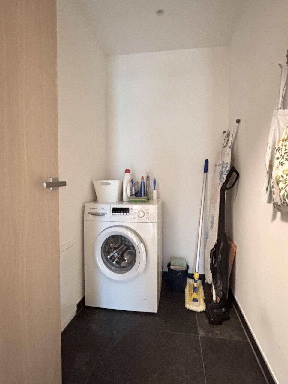Praktischer Hauswirtschaftsraum mit Waschmaschine und Reinigungsutensilien.
