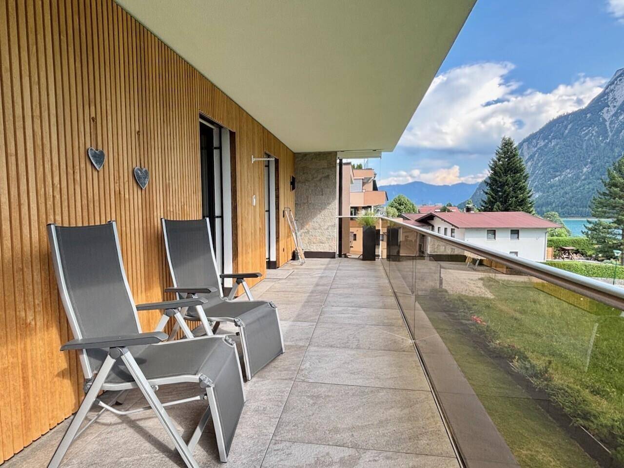 Langer Balkon mit Holzverkleidung und Liegestühlen, ideal zum Entspannen mit Bergblick.