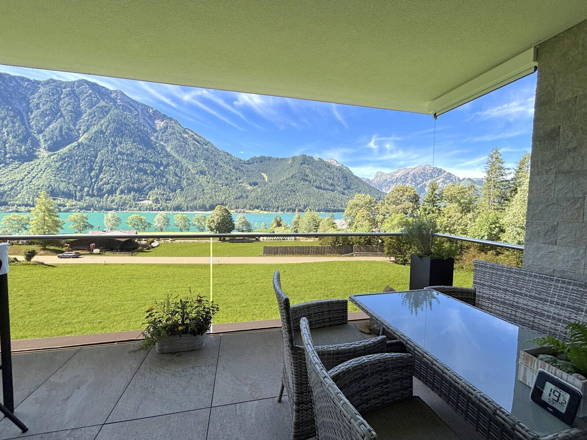 Heller Balkon mit modernen Möbeln und weitem Panoramablick auf die umliegende Berglandschaft und den See.
