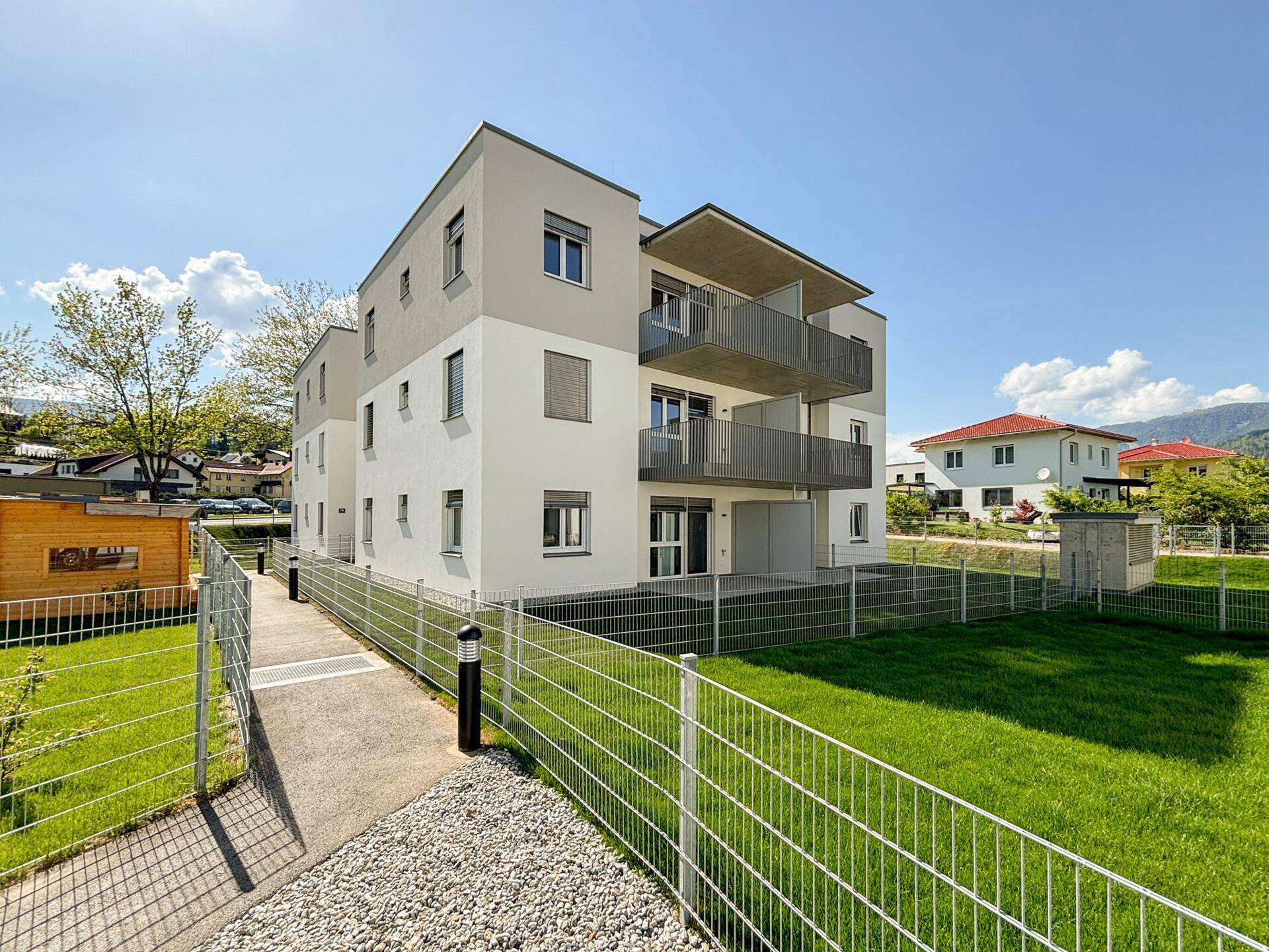 Neubau-Wohngebäude mit moderner Architektur, Balkonen und gepflegter Außenanlage.