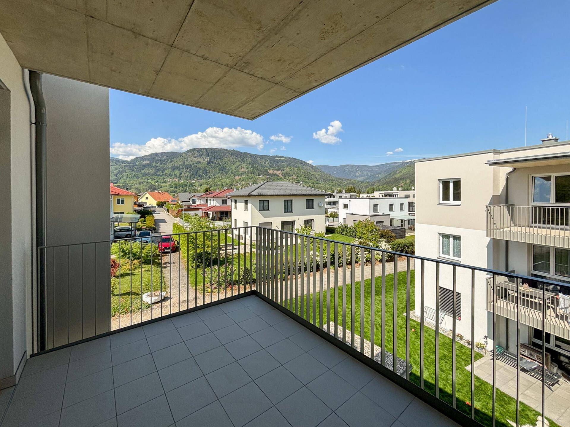 Balkon mit Fliesenboden und weitem Blick auf die Berge und grüne Umgebung.