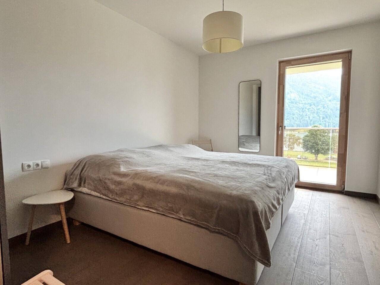 Helles Schlafzimmer mit Doppelbett, Holzboden und großen Fenstern mit Bergblick.