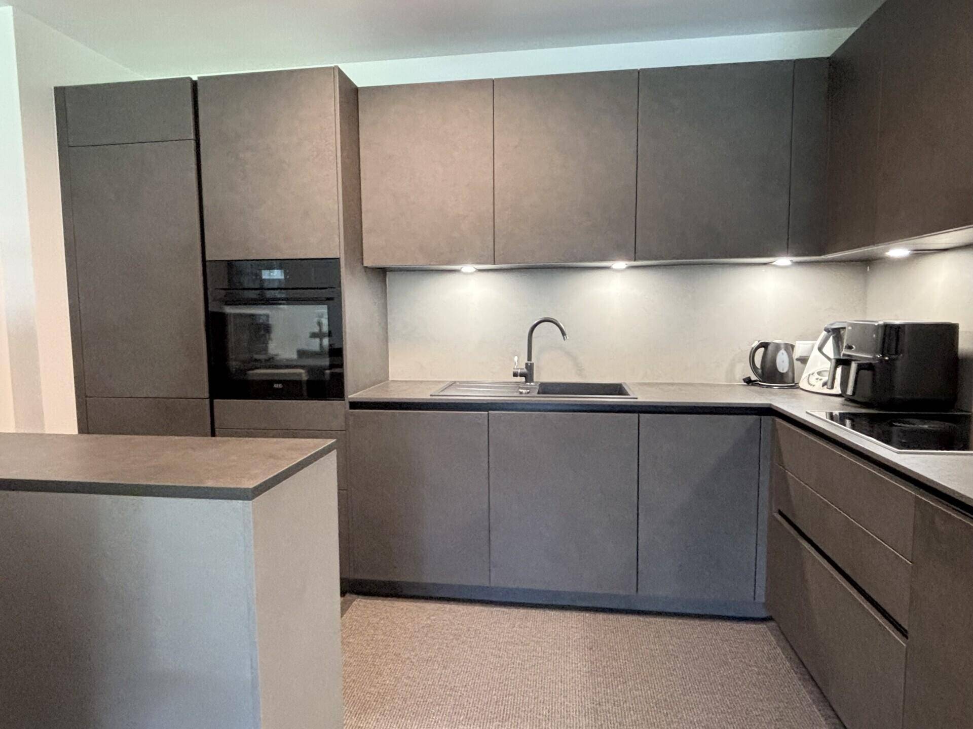 Moderne Einbauküche in Grau mit integrierten Geräten und ausreichend Arbeitsfläche.