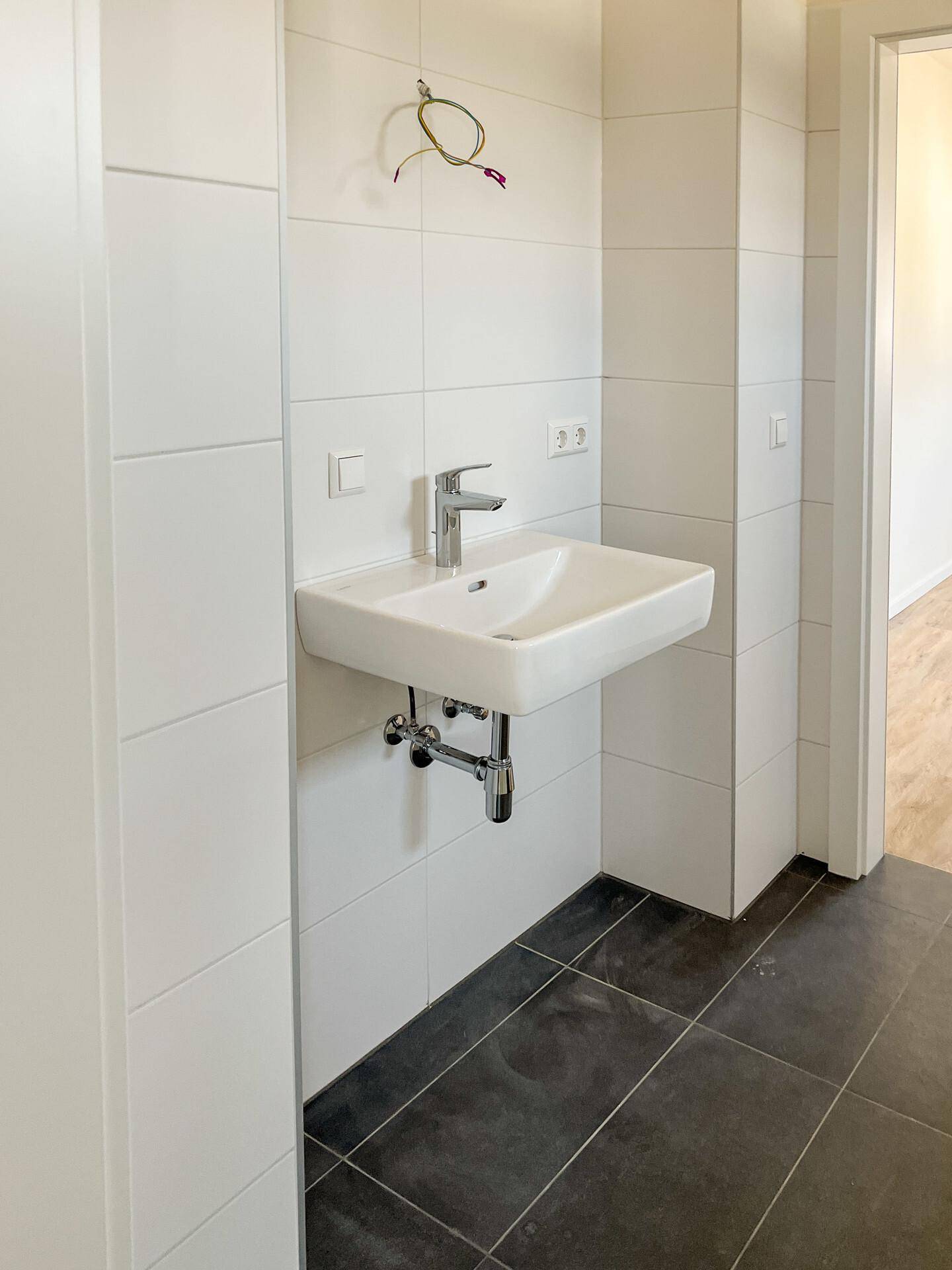 Modernes Badezimmer mit weiß gefliesten Wänden und einem Waschbecken.