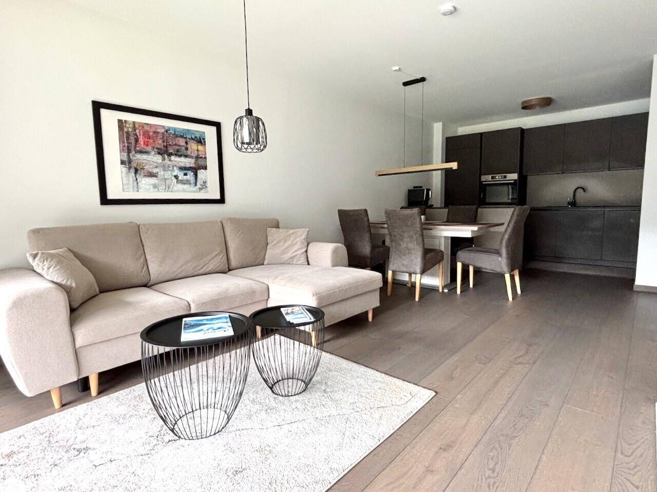 Offener Wohn- und Essbereich mit modernem Sofa, Esstisch und integrierter Küche.