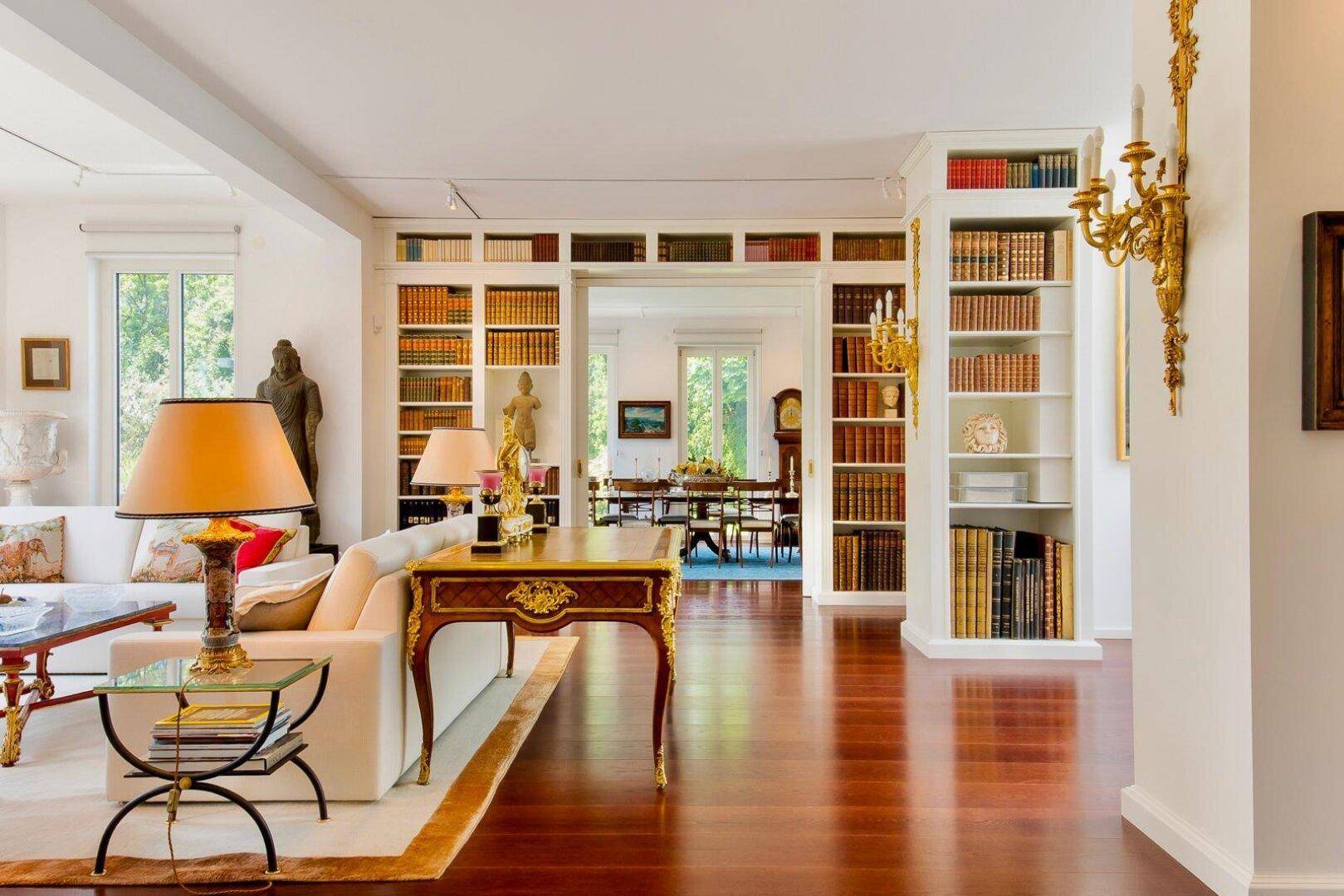 Elegantes Wohnzimmer mit glänzendem Parkettboden, eingebauten Bücherregalen und klassischer Einrichtung.