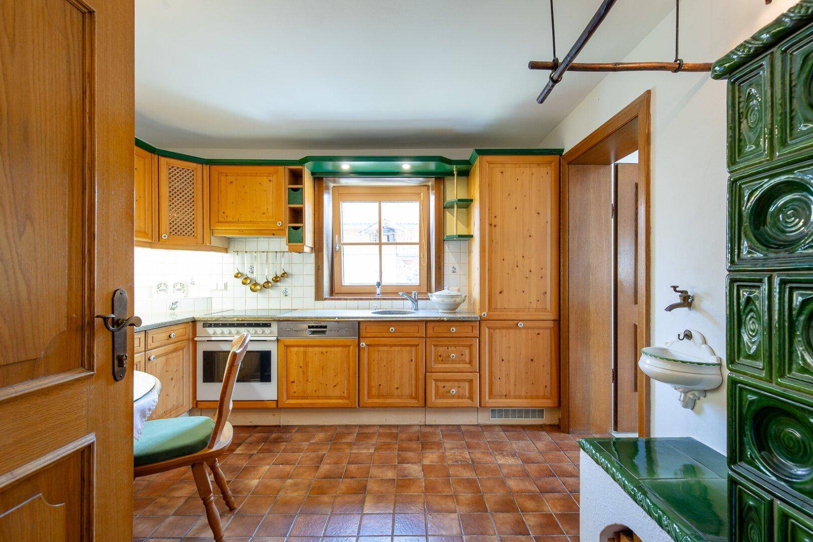 Traditionelle Holzküche mit grünen Akzenten, integrierten Geräten und einem Fenster über der Spüle.