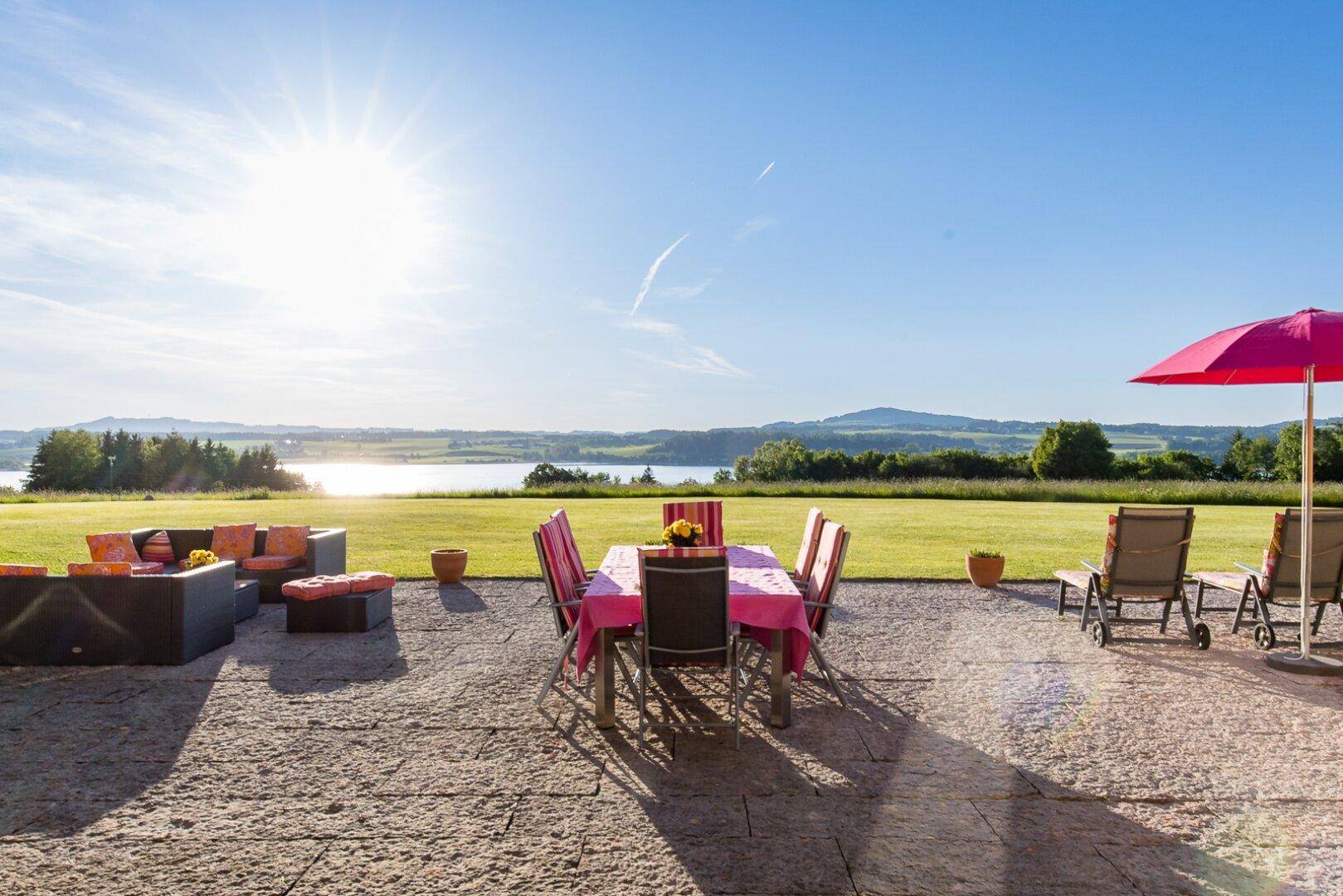 Weitläufige Sonnenterrasse mit Lounge-Möbeln, Esstisch und Panoramablick auf die Landschaft und den See.
