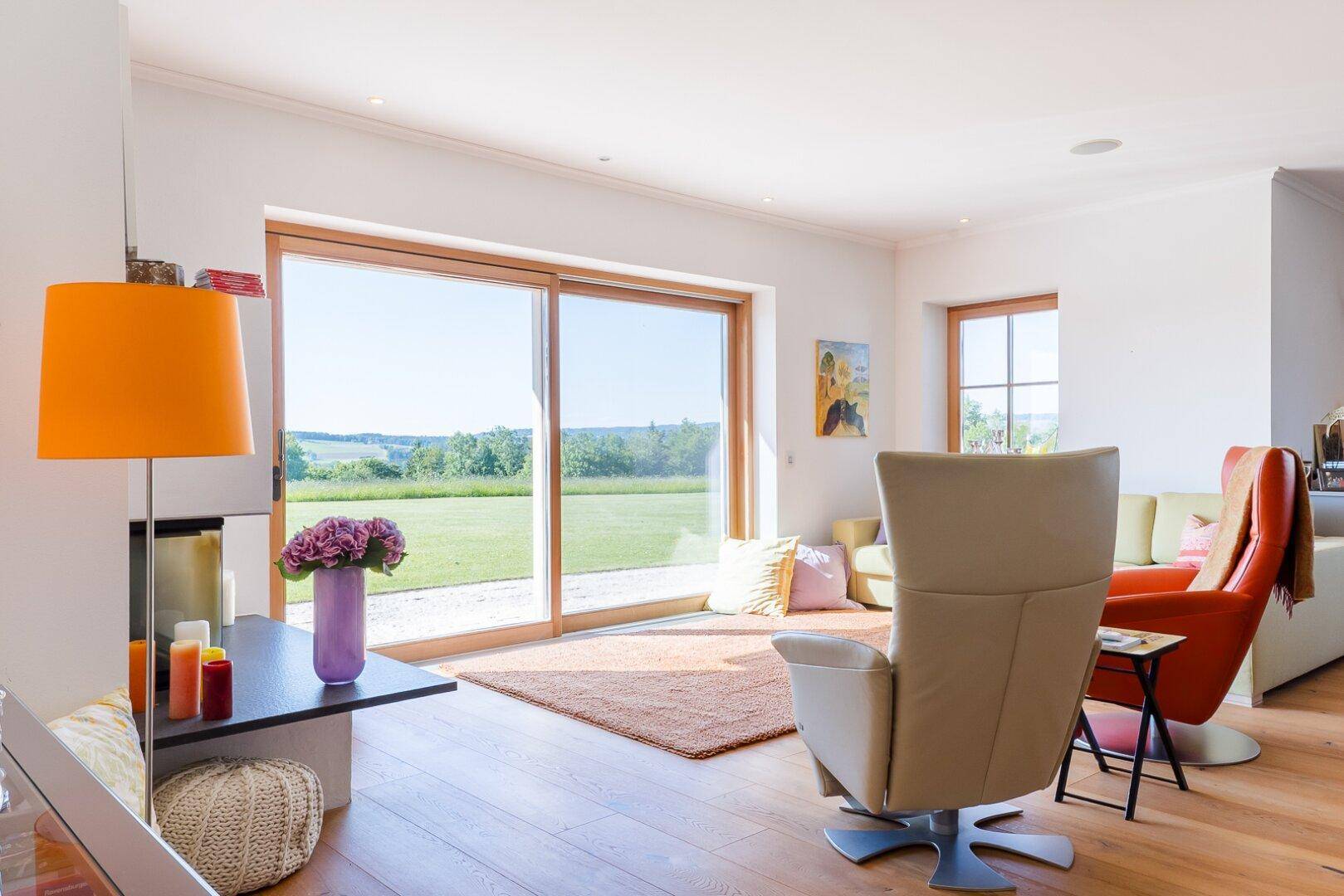 Helles Wohnzimmer mit großen Schiebetüren, Holzboden und weitem Blick ins Grüne.