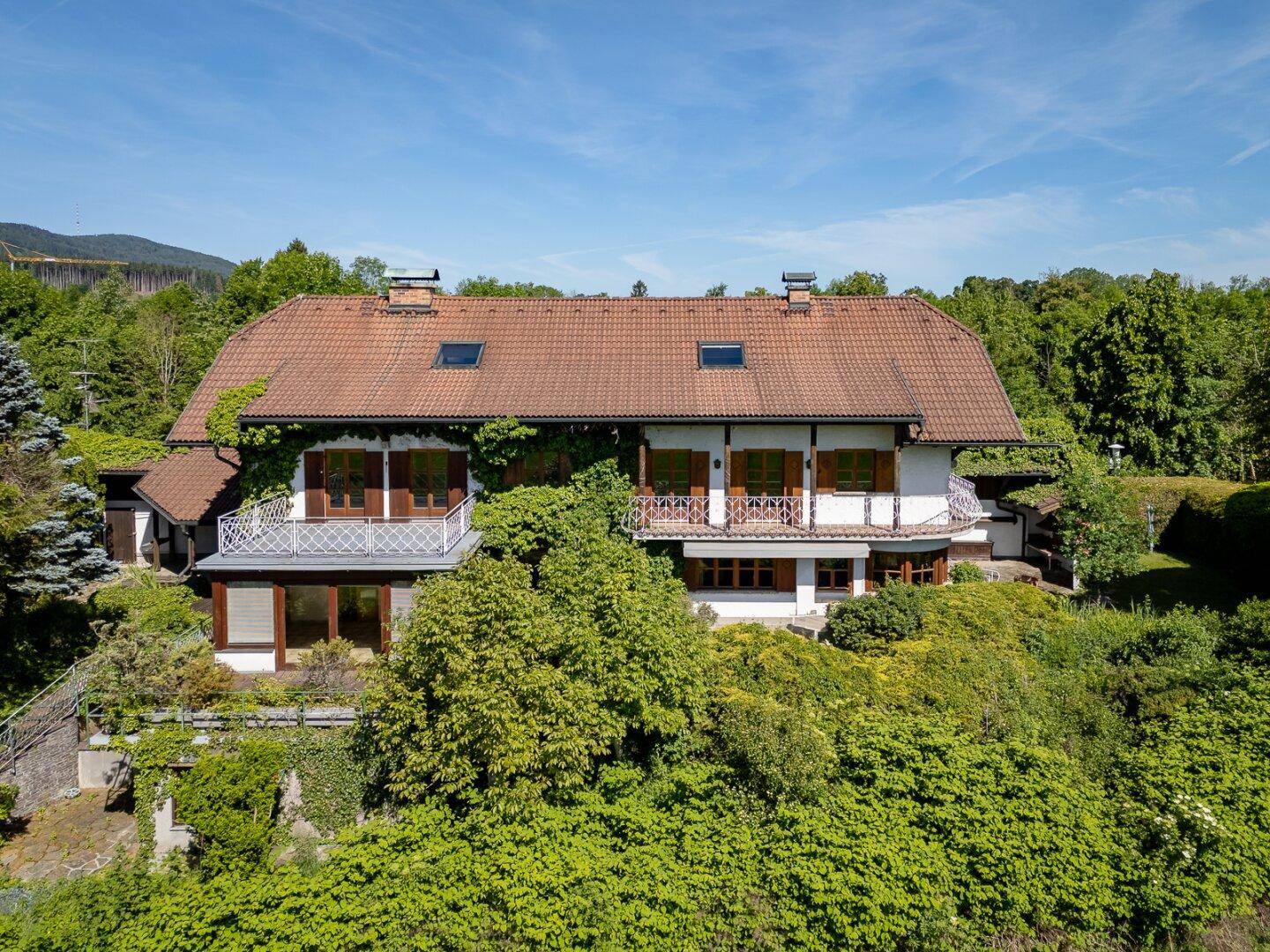 Großzügiges Anwesen umgeben von viel Grün mit Blick auf die umliegende Berglandschaft.