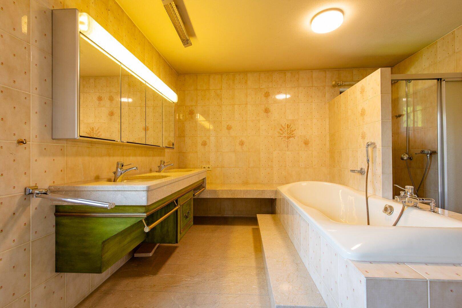 Geräumiges Badezimmer mit Doppelwaschbecken, eingebauter Badewanne und hellen Fliesen.