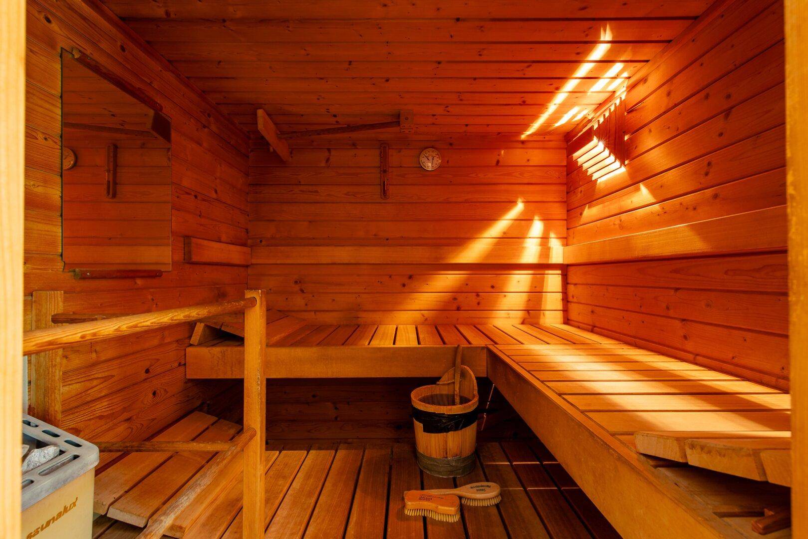 Traditionelle Holzsauna mit Sitzbänken und Saunaofen für entspannende Momente.
