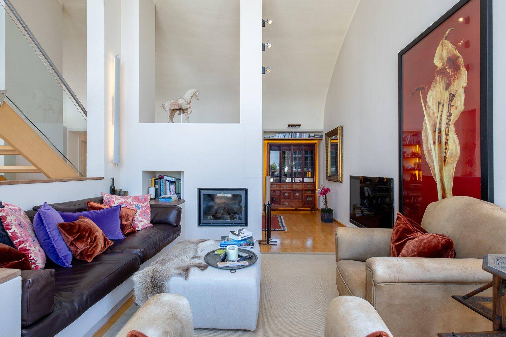 Helles Wohnzimmer mit Kamin, hohen Decken und stilvoller Einrichtung.