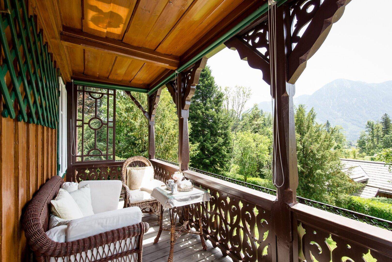 Charmant eingerichteter Holzbalkon mit kunstvollen Schnitzereien und weitem Blick ins Grüne.