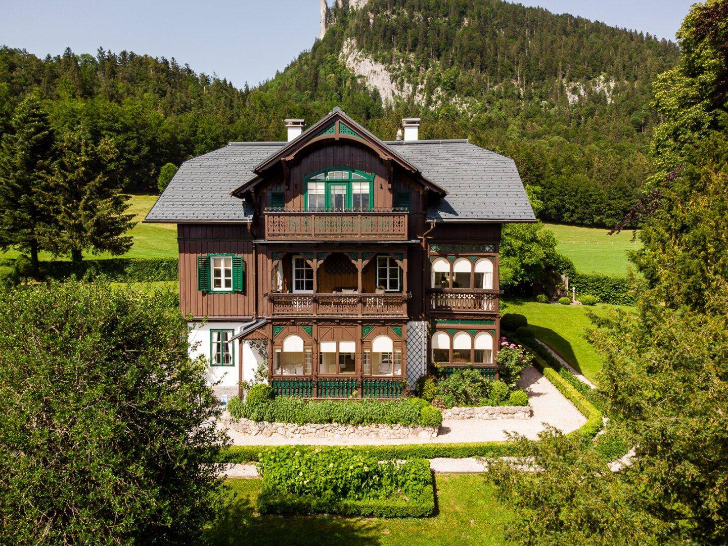 Detailansicht der historischen Fassade des Anwesens mit Holzbalkonen und grünen Fensterläden.