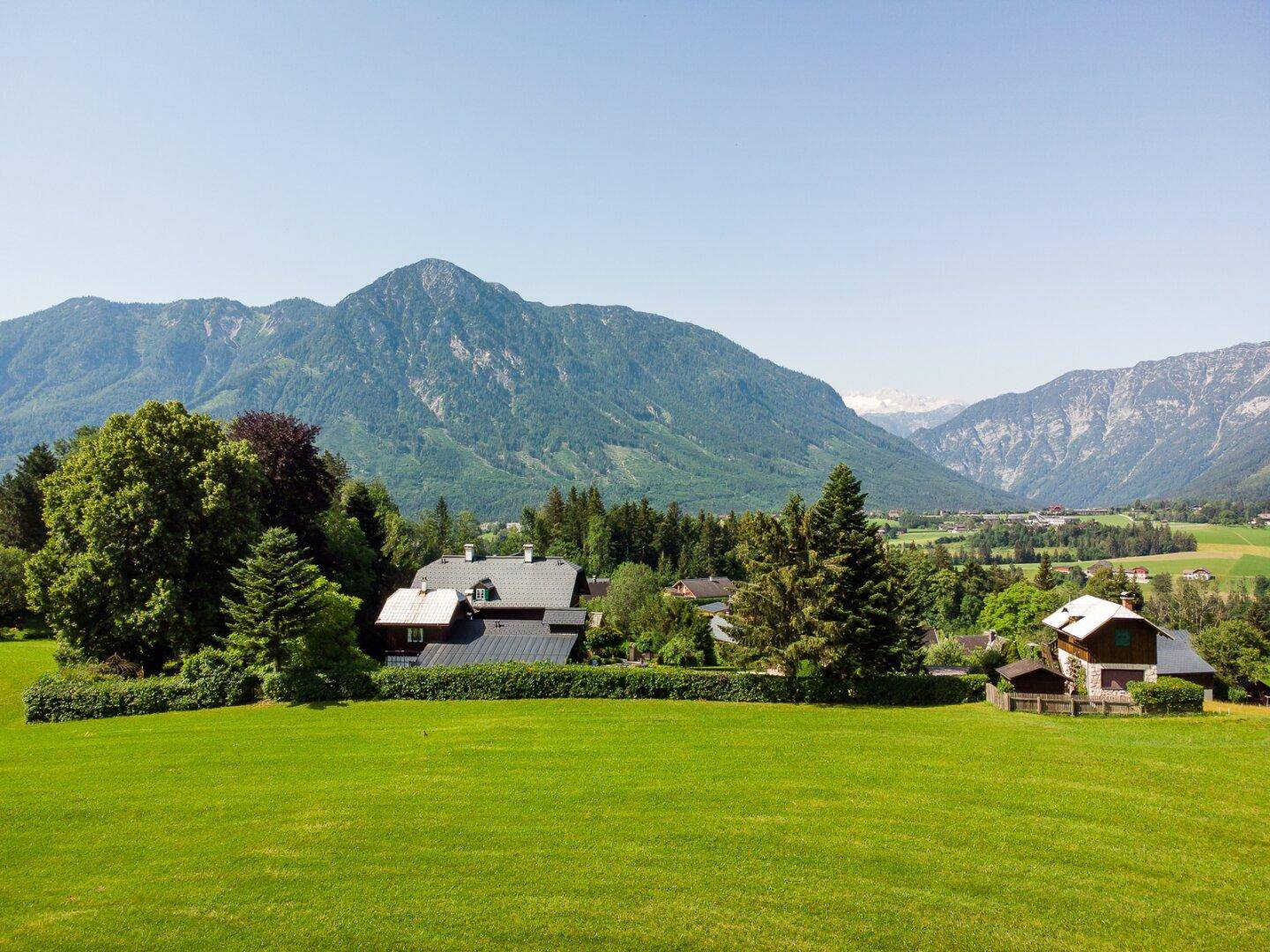 Malerischer Blick auf das Anwesen und die umliegende Berglandschaft unter blauem Himmel.