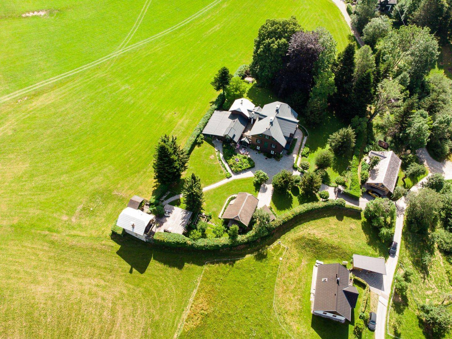 Weitläufiges Anwesen mit mehreren Gebäuden, eingebettet in grüne Felder und umgeben von Natur.