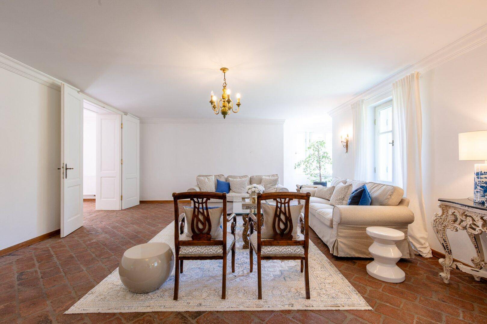 Helles Wohnzimmer mit Terrakottaboden, bequemen Sofas und klassisch-modernen Möbeln.
