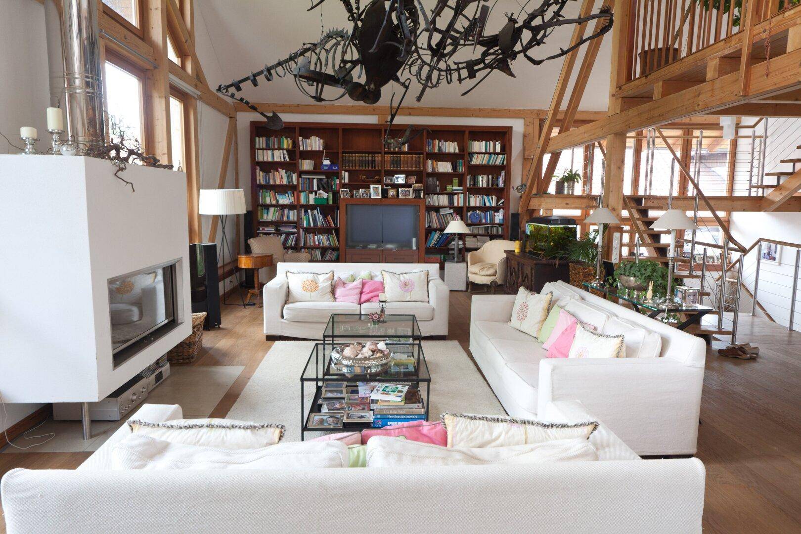 Großzügiges Wohnzimmer mit hohen Decken, Kamin und offener Galerie in modernem Stil.
