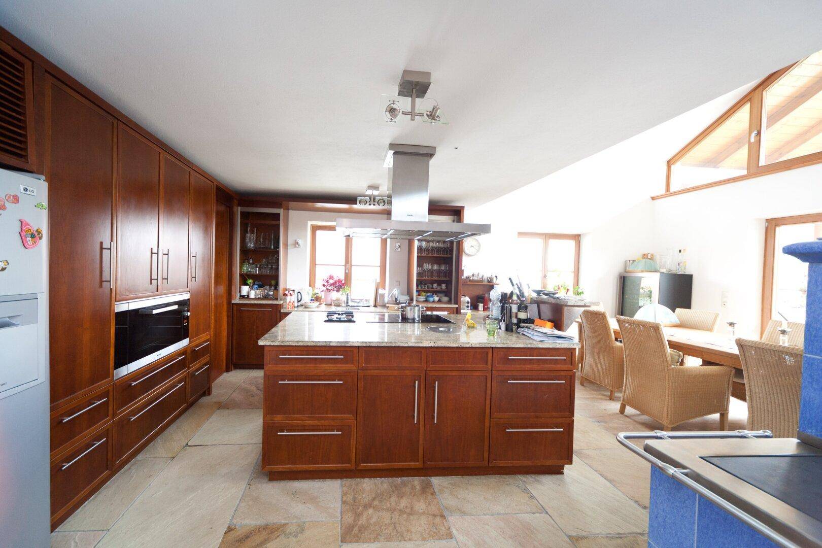 Geräumige Holzküche mit Kochinsel, Einbaugeräten und Essbereich im Landhausstil.