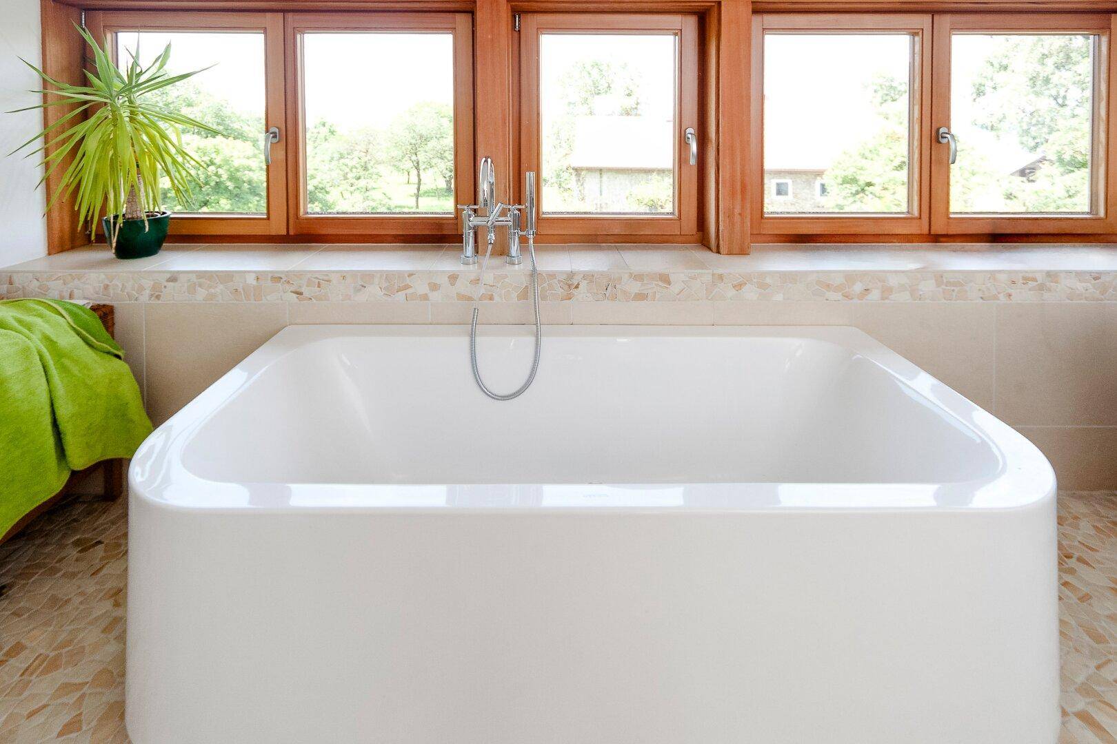 Modernes Badezimmer mit freistehender Badewanne und Fenster mit Blick ins Grüne.