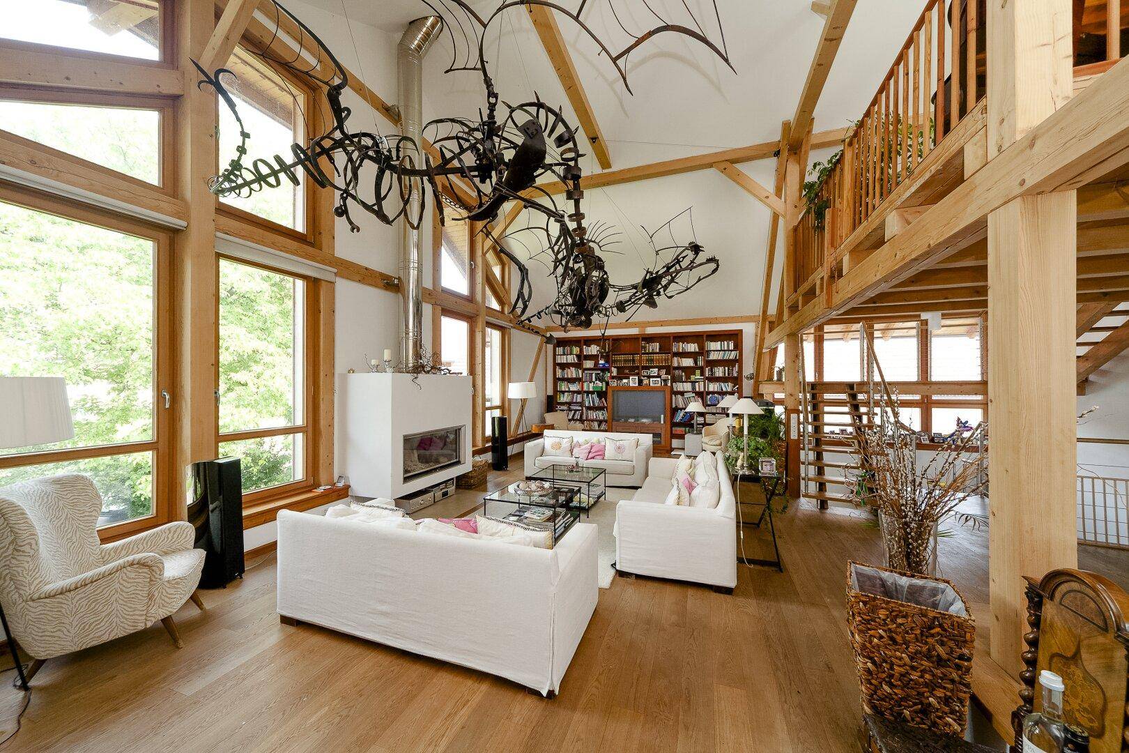 Großzügiges Wohnzimmer mit hohen Decken, Kamin und beeindruckender Holzkonstruktion.