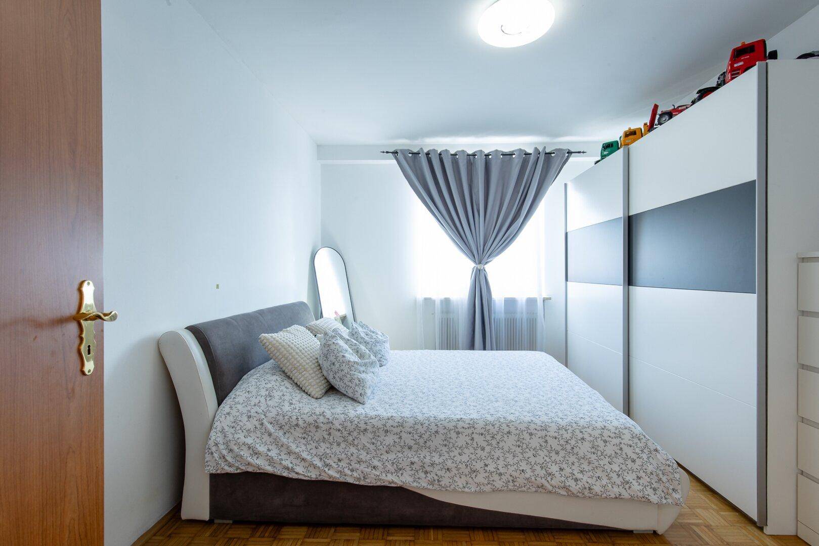 Schlafzimmer mit Doppelbett, großem Kleiderschrank und Parkettboden.