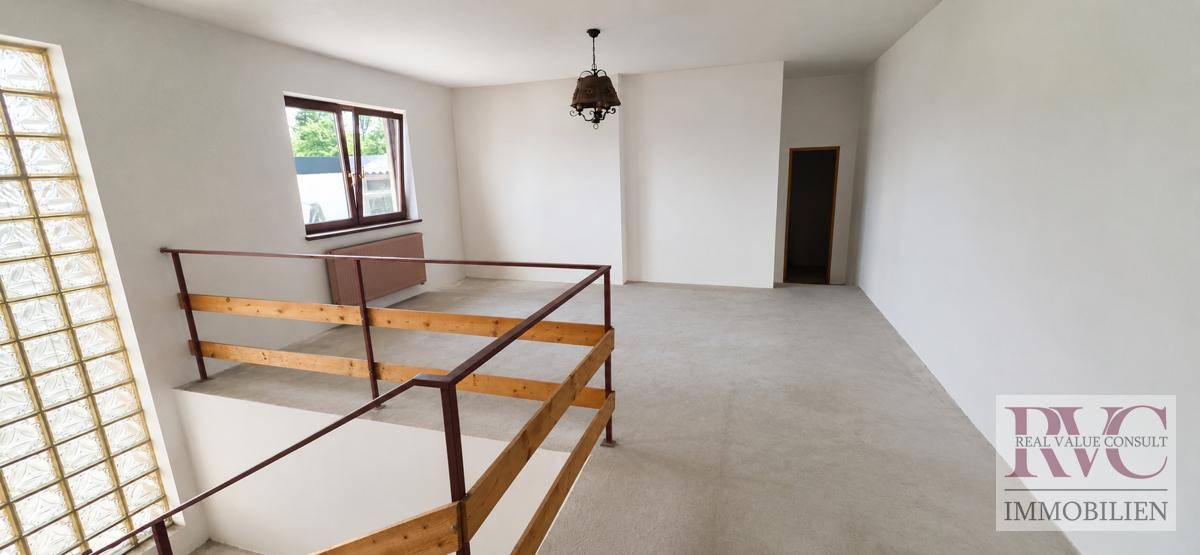 Heller Flur mit Holzgeländer und Fenster, das den oberen Bereich des Hauses beleuchtet.