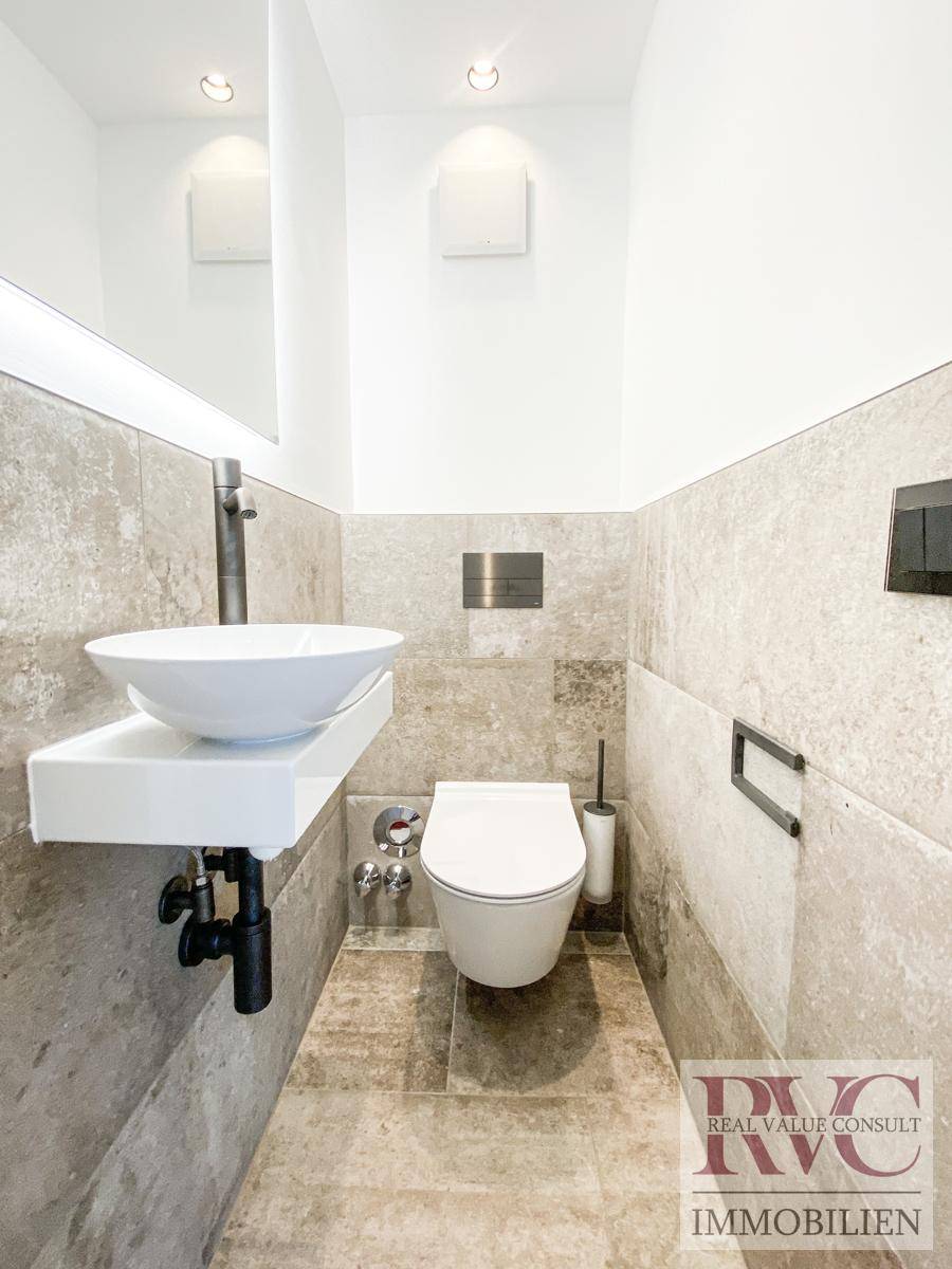 Modernes Gäste-WC mit Wand-WC, kleinem Waschbecken und stilvollen Fliesen.