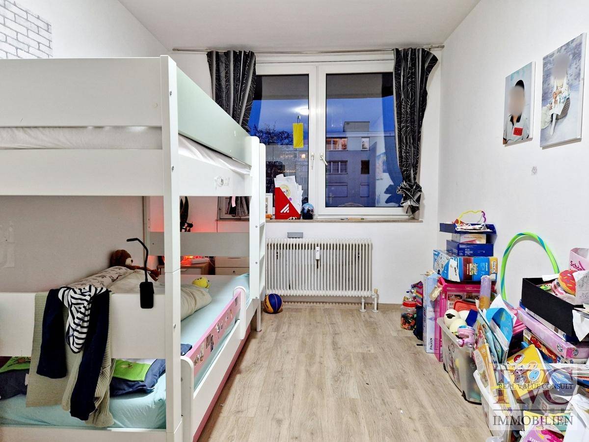 Kinderzimmer mit Etagenbett, Laminatboden und großem Fenster für viel Tageslicht.