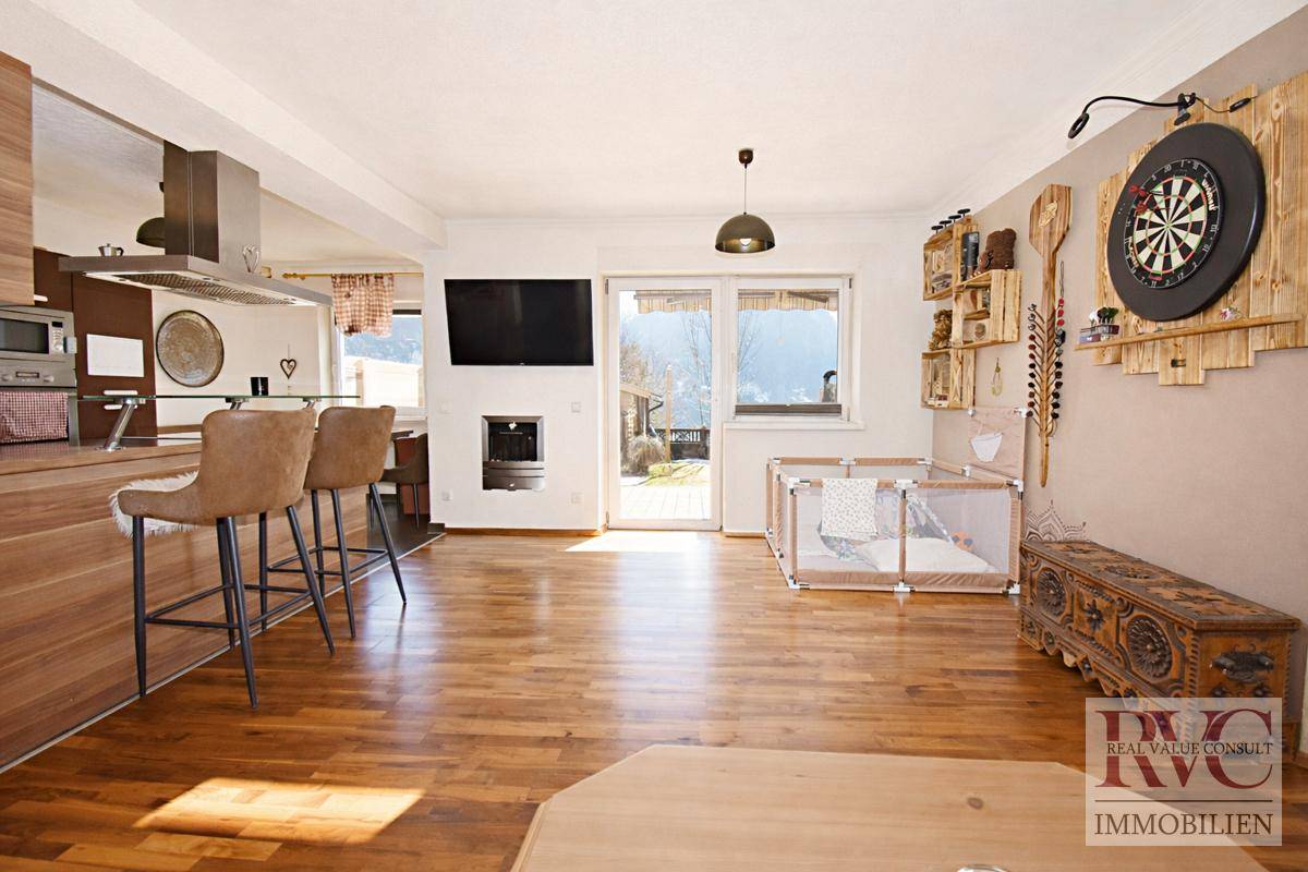 Heller, offener Wohnbereich mit moderner Holzküche, Kamin und Zugang zum Garten. Holzboden und viel Tageslicht.