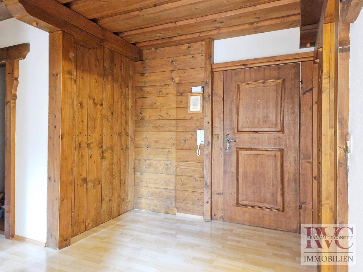 Eingangsbereich mit rustikaler Holzvertäfelung und Holztür.