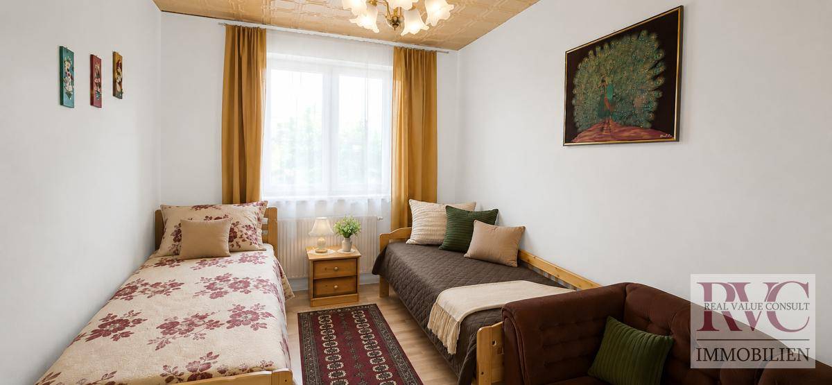 Helles Schlafzimmer mit zwei Einzelbetten, Holzboden und Fenster mit Vorhängen.