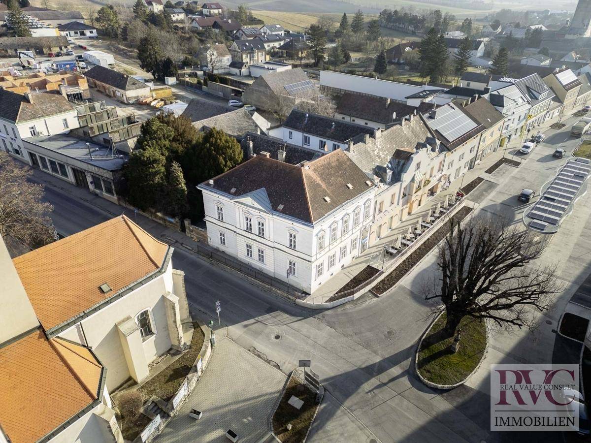Luftaufnahme des historischen Gebäudes im Zentrum einer Kleinstadt mit umliegender Landschaft.